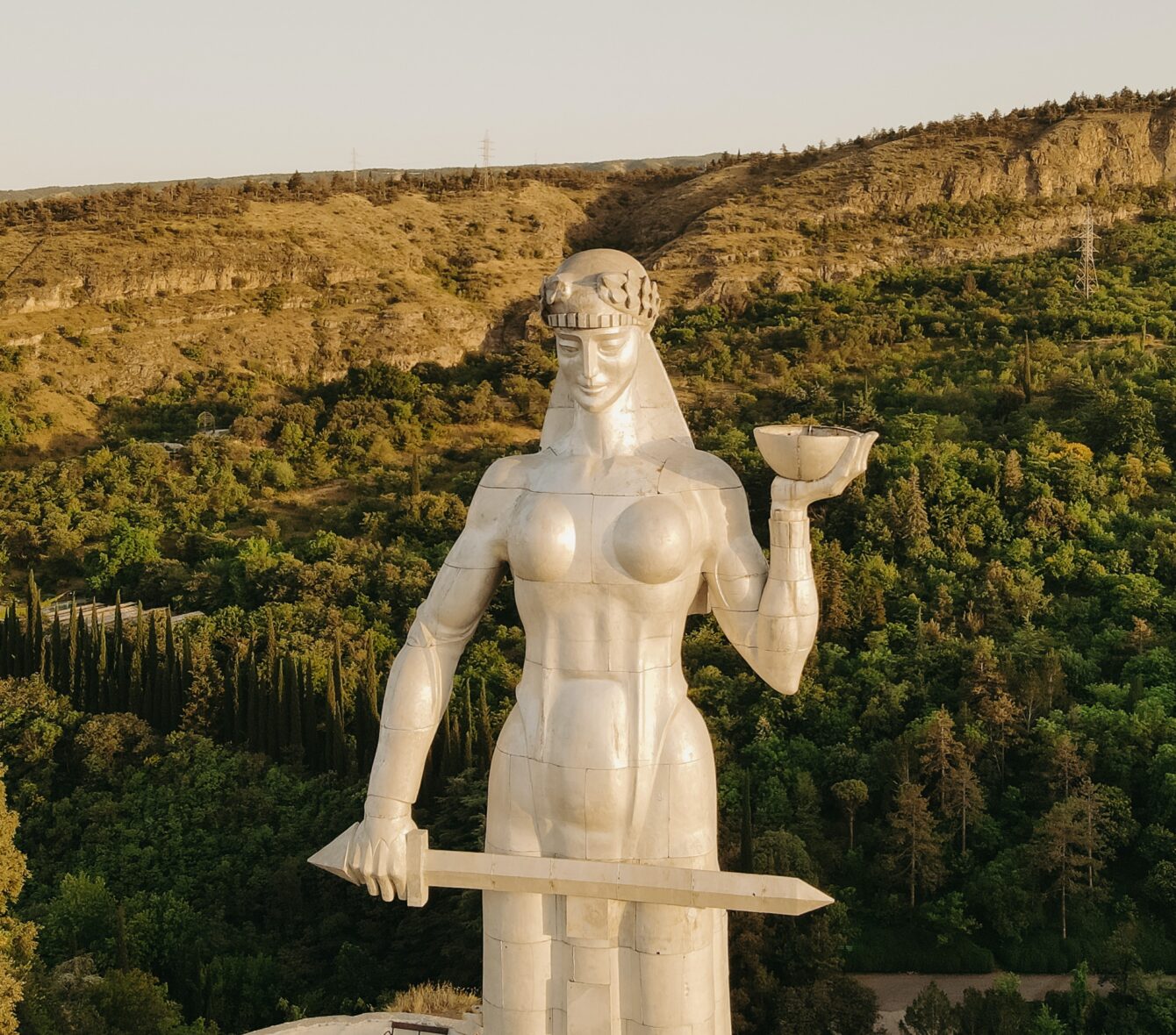 Statue holding a wine glass in one hand and a sword in the other.